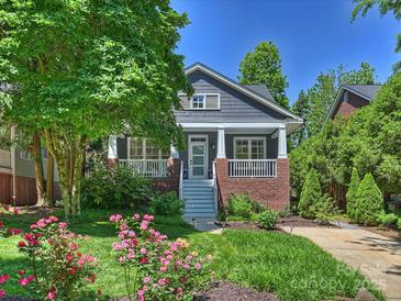Charming home with a welcoming front porch, beautiful landscaping, and colorful roses in the front yard at 2121 Club Rd, Charlotte, NC 28205