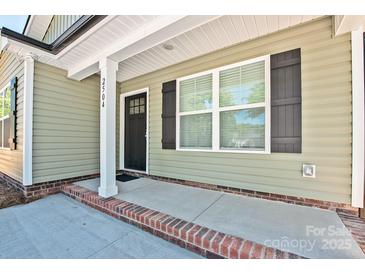 Charming front porch featuring brick detail, a black front door, and green siding at 2502-2504 Glendale Ave, Kannapolis, NC 28081