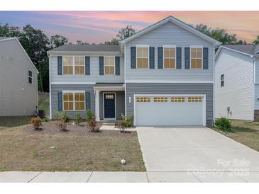 Charming two-story home featuring a two car garage, welcoming entrance and manicured landscaping at 725 Pointe Andrews Dr, Concord, NC 28025
