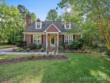 Charming two-story home featuring a well-manicured lawn, landscaped garden, and inviting front porch with decorative flower pots at 8017 Nathanael Greene Ln, Charlotte, NC 28227
