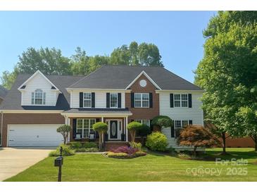 Charming two-story home featuring a manicured lawn, brick accents, black shutters, and a well-maintained front garden at 8056 Stevens Mill Rd, Matthews, NC 28104