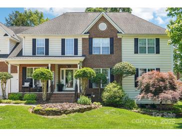 Charming two-story home featuring a brick and vinyl exterior with a well-manicured lawn and inviting front porch at 8056 Stevens Mill Rd, Matthews, NC 28104
