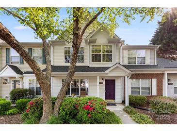 Charming townhome featuring a purple door, well-maintained landscaping, and a welcoming front porch at 12536 Hennigan Place Ln, Charlotte, NC 28214