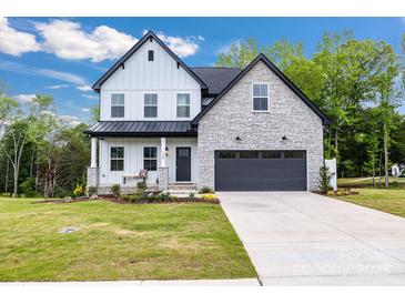 Charming two-story home featuring a stone and siding facade, black accents, and a well-manicured lawn at 1500 Nectar Way # 32, Kannapolis, NC 28083