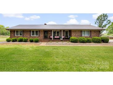 Charming brick ranch home featuring a covered front porch with updated metal roof and manicured landscaping at 1870 Sloan Rd, Mt Ulla, NC 28125