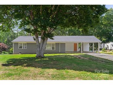 Charming single-story home with a covered carport, gray brick facade, and a large shade tree in the front yard at 2322 Hedgewood Cir, Gastonia, NC 28052