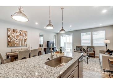 Modern kitchen featuring granite counters, stainless steel sink, and an open floor plan to the dining and living areas at 2460 Hedgecliff Rd, Kannapolis, NC 28025