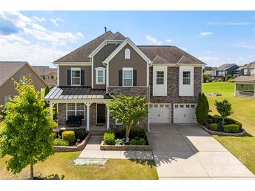 Beautiful two-story home featuring a manicured lawn, 3-car garage, and inviting covered front porch at 2511 Carnation Dr, Harrisburg, NC 28075