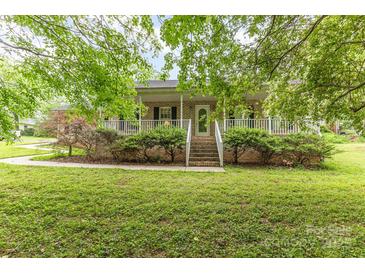 Charming brick home featuring a welcoming front porch and lush, green landscaping at 302 6Th Sw St, Conover, NC 28613