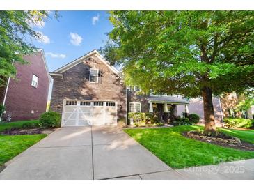 Beautiful two-story home with stone exterior, attached garage, manicured lawn, and mature trees at 10115 Paxton Run Rd, Charlotte, NC 28277