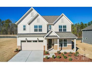 Two-story home with a neutral color palette, a two-car garage, and a beautifully landscaped front yard at 2008 Waxhaw Crossing Dr, Waxhaw, NC 28205
