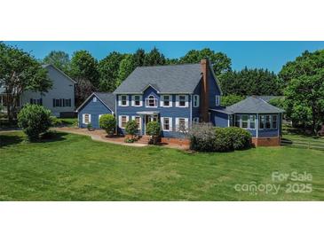 Charming two-story home with blue siding, white trim, brick chimney, and mature landscaping at 106 Chatworth Ln, Mooresville, NC 28117