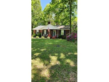 Charming brick home with an American flag, manicured lawn, and mature trees at 10624 Wood Meadow Dr, Charlotte, NC 28227