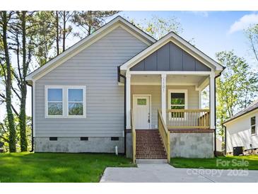 Inviting single-story home featuring a cozy front porch with gray siding and well-manicured lawn at 1101 Kenly St, Salisbury, NC 28144