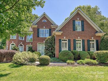 Beautiful brick home featuring a well-manicured lawn and vibrant green shrubbery at 16511 Bridgehampton Club Dr, Charlotte, NC 28277