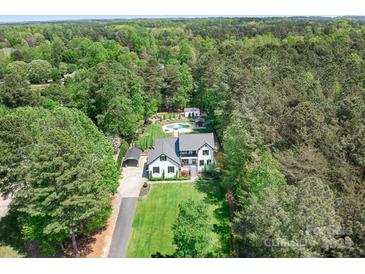 Stunning aerial view of the white house with lush green landscaping, pool, and surrounding forest at 317 Marietta Rd, Mooresville, NC 28117