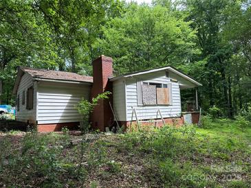 Exterior view of a white house with a brick chimney surrounded by lush green trees at 455 Running Brook Rd, Midland, NC 28107