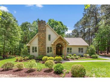 Charming home with a stone chimney, arched entryway, and manicured landscaping at 6599 Majestic Pine Dr, Vale, NC 28168