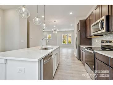 Bright kitchen features stainless appliances, a stylish island with a sink, and modern pendant lighting at 842 Van Every St, Charlotte, NC 28205