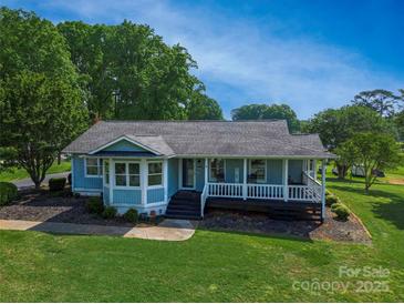 Charming light blue home featuring a inviting front porch and lush green lawn in a beautiful, tree-filled setting at 174 Perrin Dr, Mooresville, NC 28117
