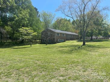 Expansive lawn and mature trees surround this brick home with bright, white-trimmed windows at 205 Rudolph Rd, Salisbury, NC 28146