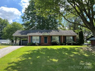 Charming brick ranch-style home with green shutters, mature trees, and a lush, expansive front lawn at 235 Cherokee Ln, Salisbury, NC 28147