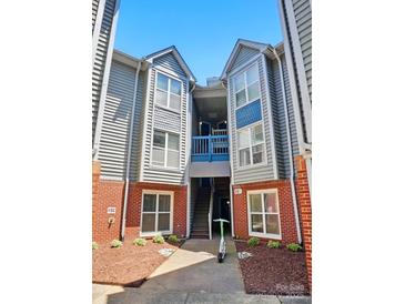 Charming two-story condo with brick accents and a blue-painted walkway against a clear sky at 529 N Graham St # 3F, Charlotte, NC 28202