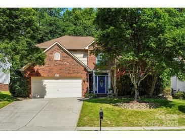 Charming two-story brick home with lush green lawn, mature trees, and a two car garage at 5818 Downfield Wood Dr, Charlotte, NC 28269