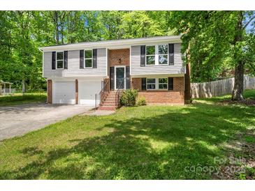 Split-level home features a brick facade, two-car garage, and a well-manicured lawn at 6839 Wagon Oak Rd, Charlotte, NC 28212