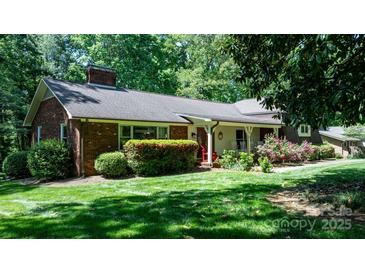 Charming single-story brick home with a lush green lawn, mature trees, and vibrant landscaping at 701 5Th Ne Ave, Conover, NC 28613