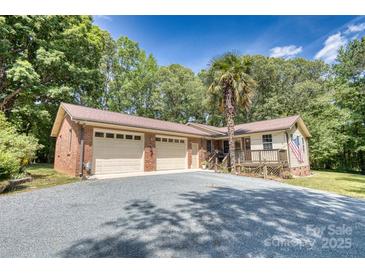 Charming home featuring a two-car garage, front porch, and a spacious driveway surrounded by mature trees at 3116 Old Montgomery Place Rd, Monroe, NC 28112