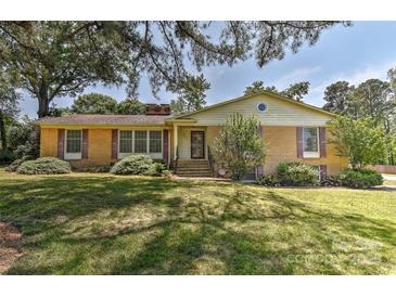 Charming brick home featuring a well-maintained lawn, mature trees, and a welcoming entrance at 385 Gum Branch Rd, Charlotte, NC 28214