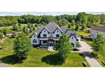 Stunning aerial view of a modern, white-painted brick home with manicured lawn and mature trees at 1005 Grand Oak Dr, Waxhaw, NC 28173