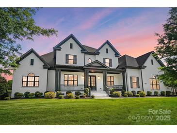 Stunning two-story white brick home with a covered front porch and beautiful landscaping at 1005 Grand Oak Dr, Waxhaw, NC 28173