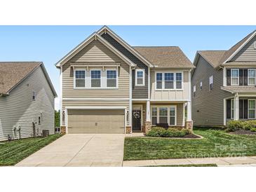 Charming two-story home with a manicured lawn, attached garage, and welcoming front porch at 128 Championship Dr, Mooresville, NC 28115
