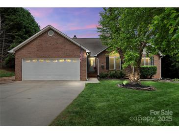 Charming brick home with a well-manicured lawn, two-car garage, and inviting front entrance at dusk at 2315 Perry Rd, Denver, NC 28037