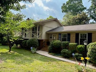Inviting home with a charming front yard, manicured greenery, and a covered porch perfect for relaxing outdoors at 5938 Sharon Rd, Charlotte, NC 28210