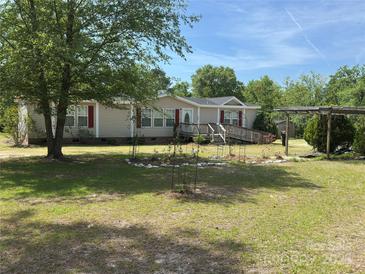 Charming ranch-style home with beige siding, red shutters, a ramp to the front door, and a spacious front yard at 7494 Flat Creek Rd, Lancaster, SC 29720