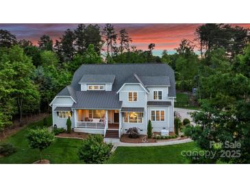 Stately two-story home featuring a covered front porch and lush landscaping against a backdrop of mature trees at 106 Thunder Hill Rd, Mooresville, NC 28117