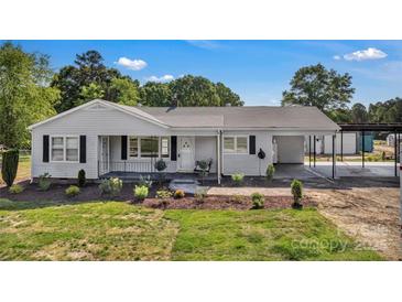 Charming single-story home featuring classic siding, black shutters, a covered porch and attached carport at 159 Old Home Pl, China Grove, NC 28023