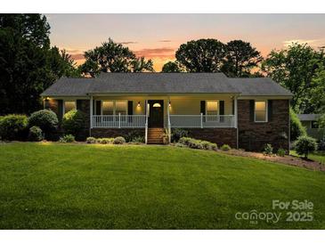 Charming ranch-style home with a brick facade, covered porch, and lush front lawn at sunset at 3712 Eaglebrook Dr, Gastonia, NC 28056