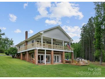 Expansive two-story home featuring a charming wooden deck, a spacious lawn, and inviting outdoor spaces for leisure and enjoyment at 281 Emerald Shores Rd, Mount Gilead, NC 27306