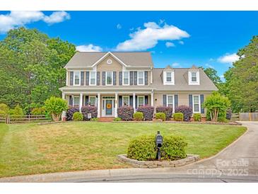 Charming two-story home with a manicured lawn, front porch, beautiful shrubbery, and classic architectural details at 3864 Meadow Ridge Nw Dr, Concord, NC 28027