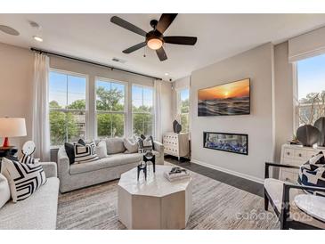 Bright living room with large windows, fireplace, modern ceiling fan, and stylish contemporary furniture and decor at 743 Hoke Ln, Davidson, NC 28036