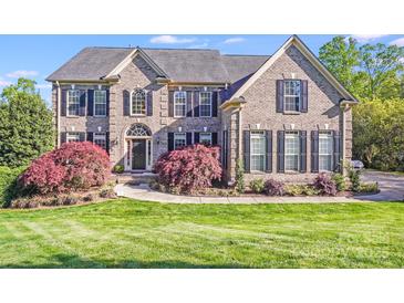 Beautiful brick home featuring manicured lawn, lush landscaping and black shutters at 9433 Stonebridge Way, Mint Hill, NC 28227