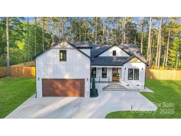 Charming craftsman home boasting board and batten siding, black trim, and a striking wood garage door at 10125 Bethel Church Rd, Midland, NC 28107