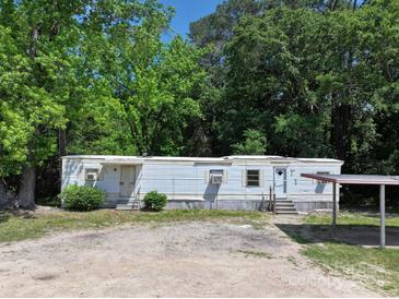 Modest single-story home featuring light blue siding and a practical covered parking area at 1029 Sullivan St, Wadesboro, NC 28170