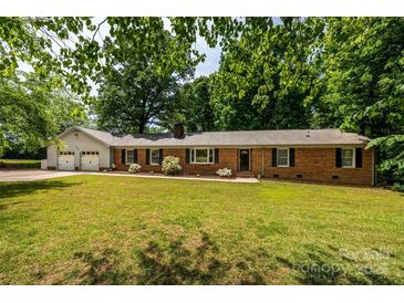 Charming brick ranch home with a lush, green front yard and mature trees at 13030 Mayes Rd, Huntersville, NC 28078