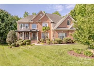 Charming two-story red brick home with lush landscaping and a welcoming front porch at 3304 Danhill Pl, Matthews, NC 28105
