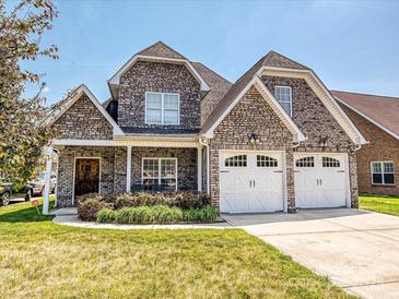 Charming brick home with a two-car garage and a well-manicured lawn on a sunny day at 4562 Lanstone Sw Ct, Concord, NC 28027